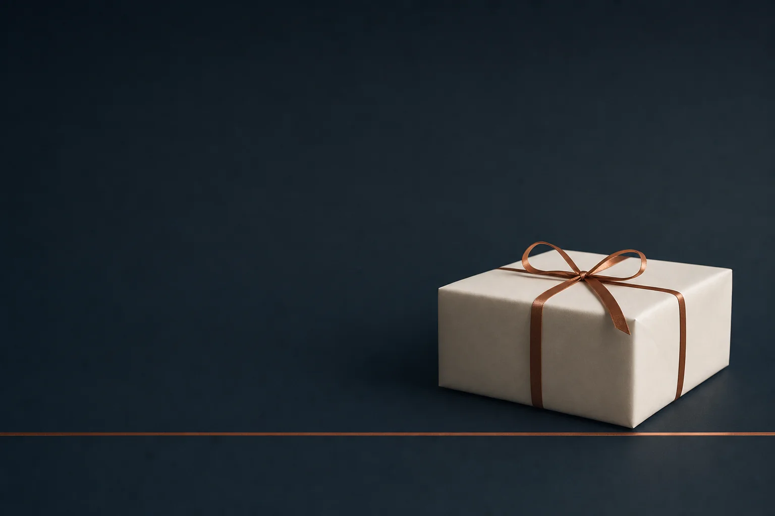 A single blank ivory wrapped parcel tied with a copper ribbon at the right of a dark navy table, with a thin copper line inlaid straight across the table in front of it.